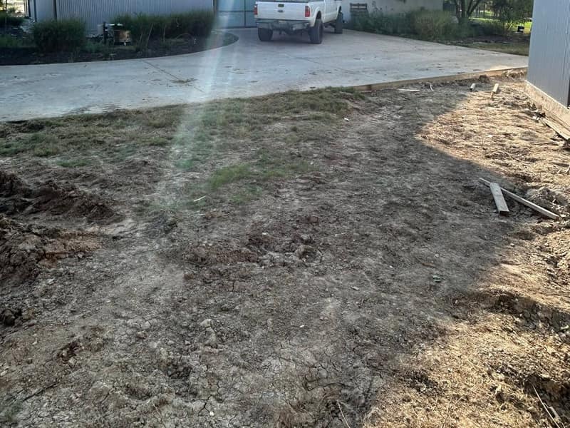 White metal barndominium with a white pickup on the new concrete driveway
