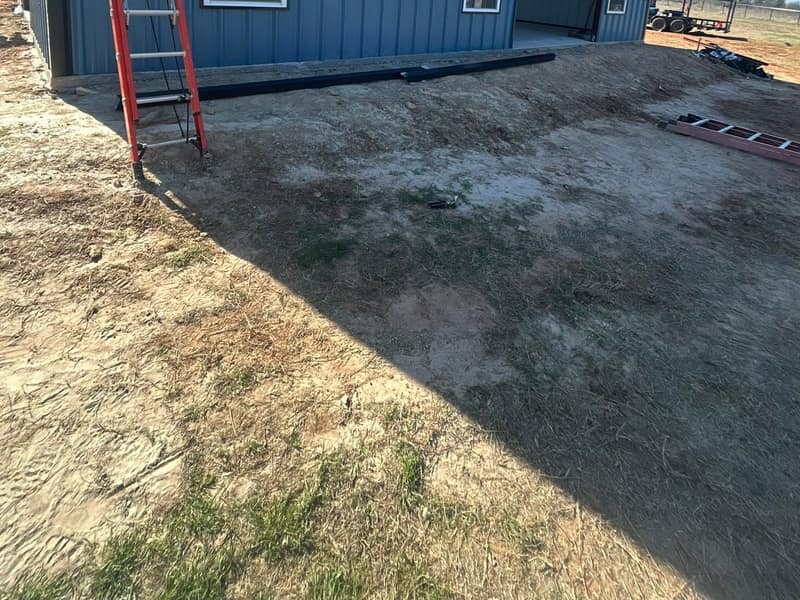 Side wall of a white metal shop with dark blue wainscot, three windows and a ladder against the eave