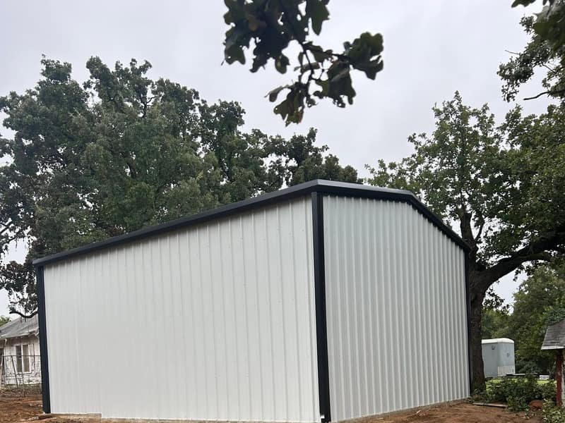 White metal shop with black trim, gable end on freshly graded dirt