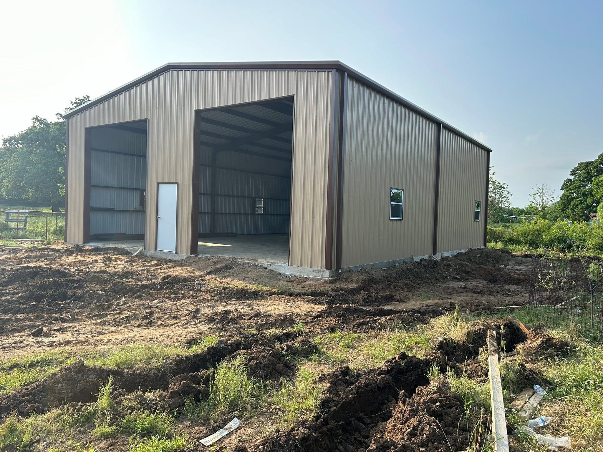 Tall metal RV cover with an enclosed back wall on a gravel pad