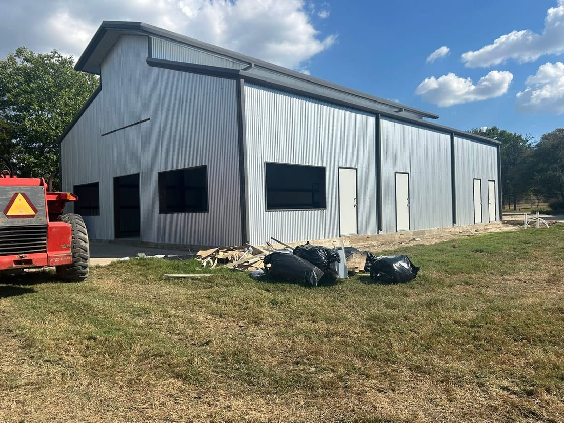 White metal barndominium shell with a red lift out front