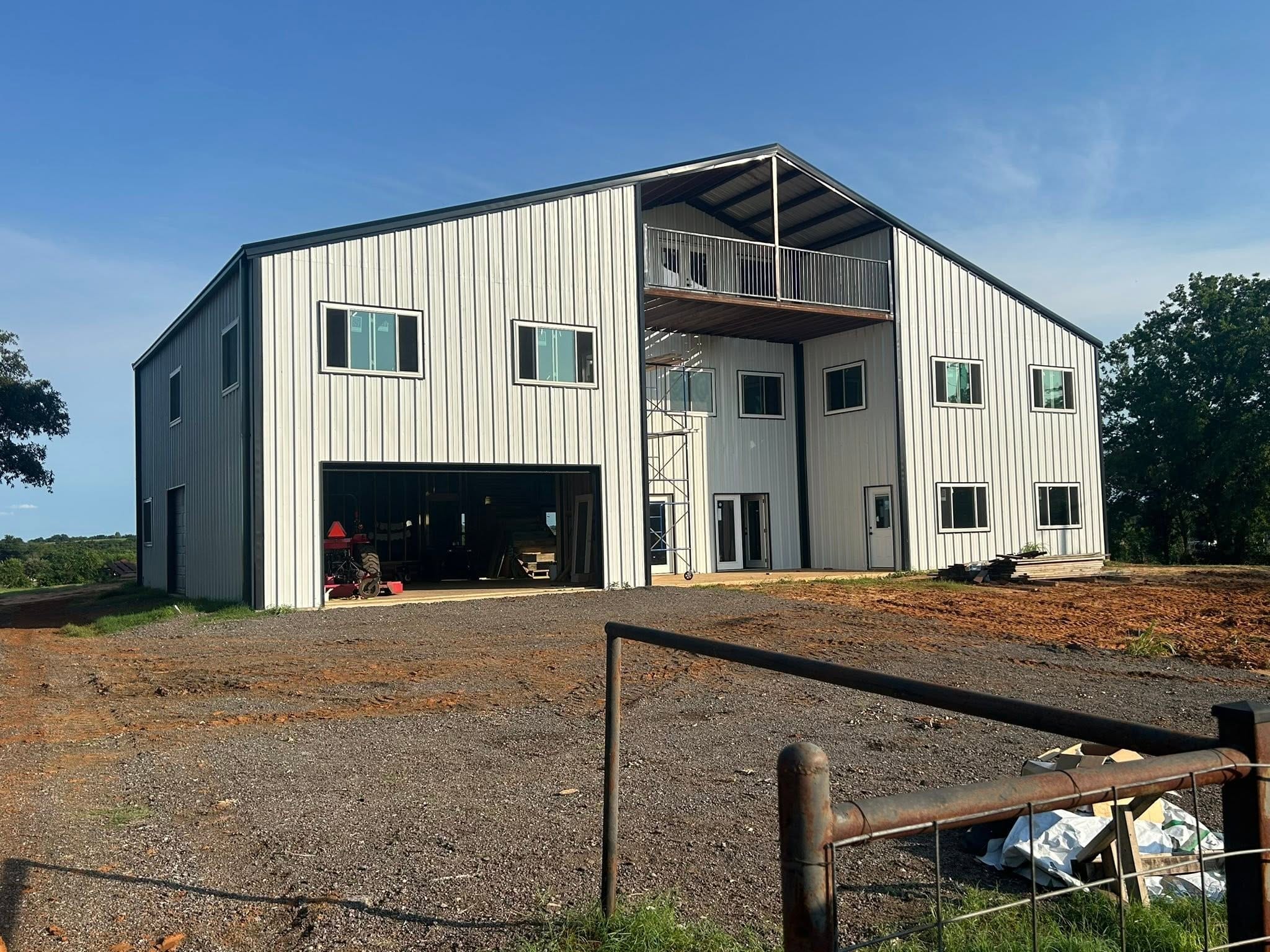 Two-story white metal barndominium with a covered balcony, built on-site by Galvan MBS